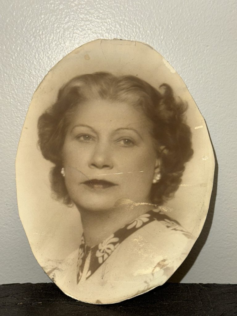 A vintage sepia-toned oval portrait of an elegant woman with wavy hair and pearl