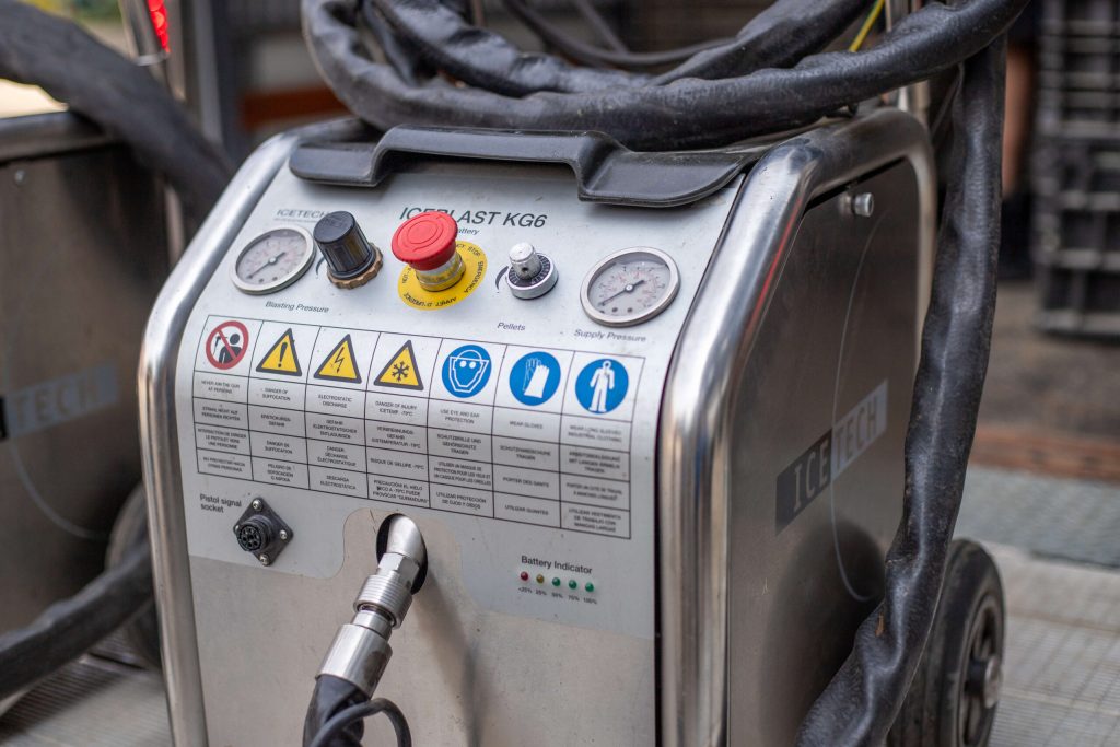 Close-up of an ICETECH ICEBLAST KG6 dry ice blasting machine's control panel with gauges and safety warnings.