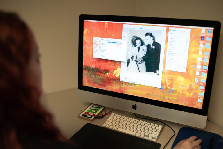 A person views a vintage black and white wedding photo on an Apple iMac screen.