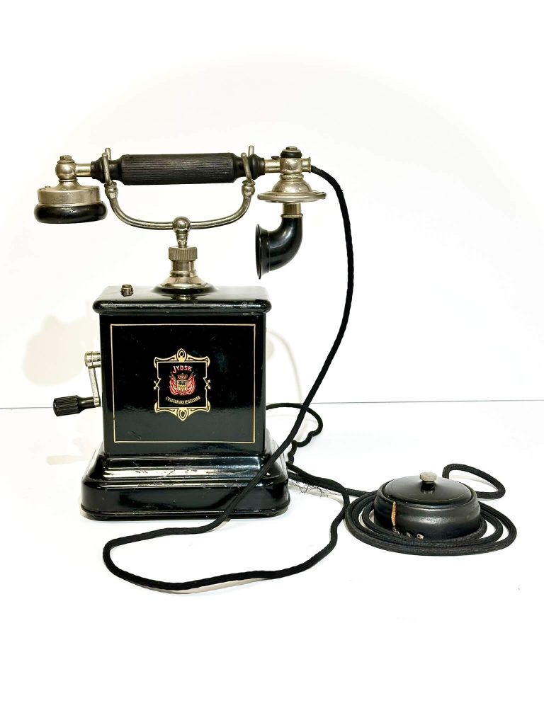 An antique black Jydsk crank telephone with a separate receiver and ringer unit on