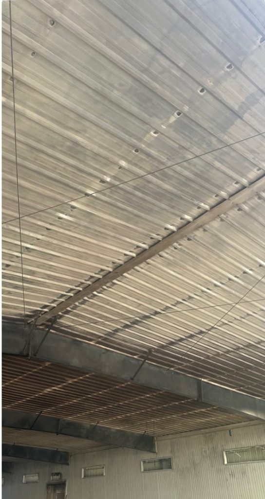 Interior view of a corrugated metal roof, slatted ceiling, and upper walls with small