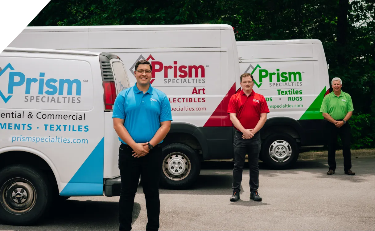 Three Prism employees in front of branded service vans