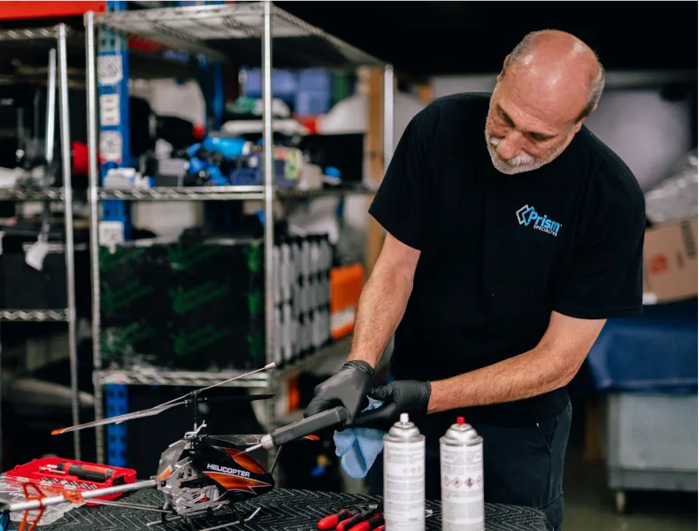 Prism technician cleaning an RC helicopter in a workshop