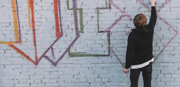 Person standing before a graffiti-covered exterior wall
