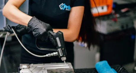 Technician using a pneumatic tool on electronics in a workshop