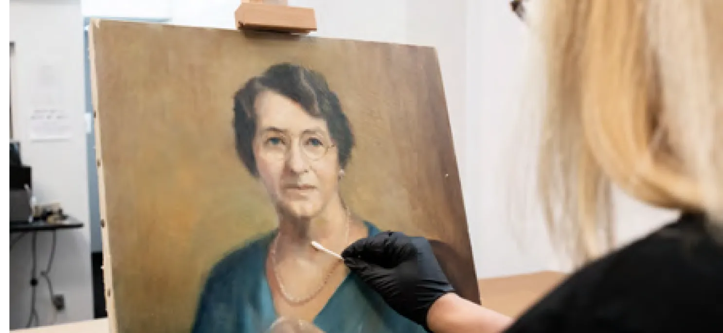 Art restorer working on an oil portrait in the studio