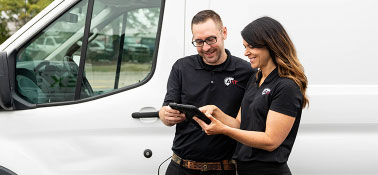 Prism Specialties experts looking at a tablet next to a white van