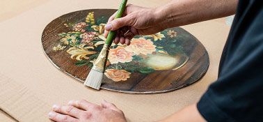 Person brushing piece of art