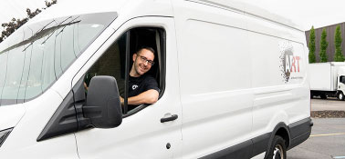 Man smiling at the camera from inside a white Prism Specialties truck