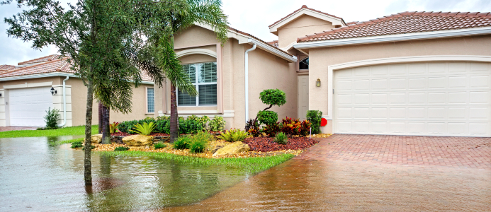 A home’s driveway and yard are flooded from a recent storm.