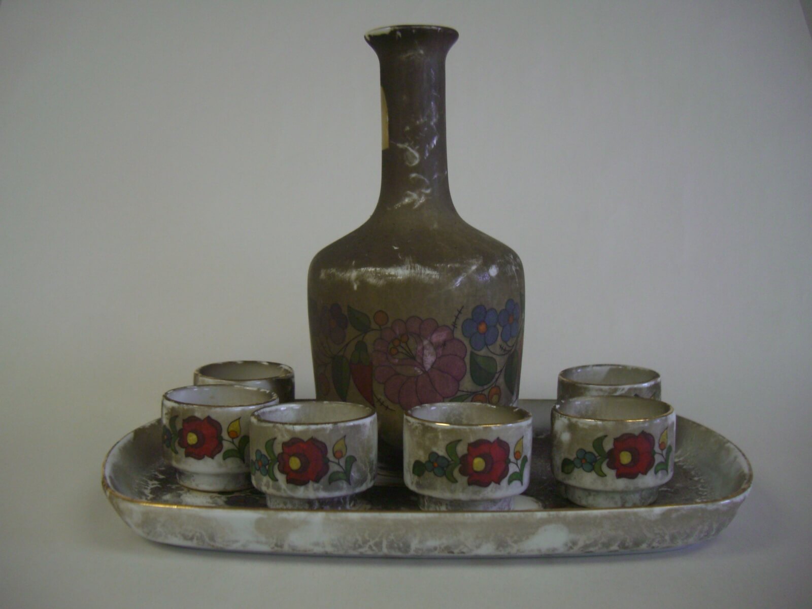 Hand-painted porcelain decanter set with heavy smoke and soot damage before restoration