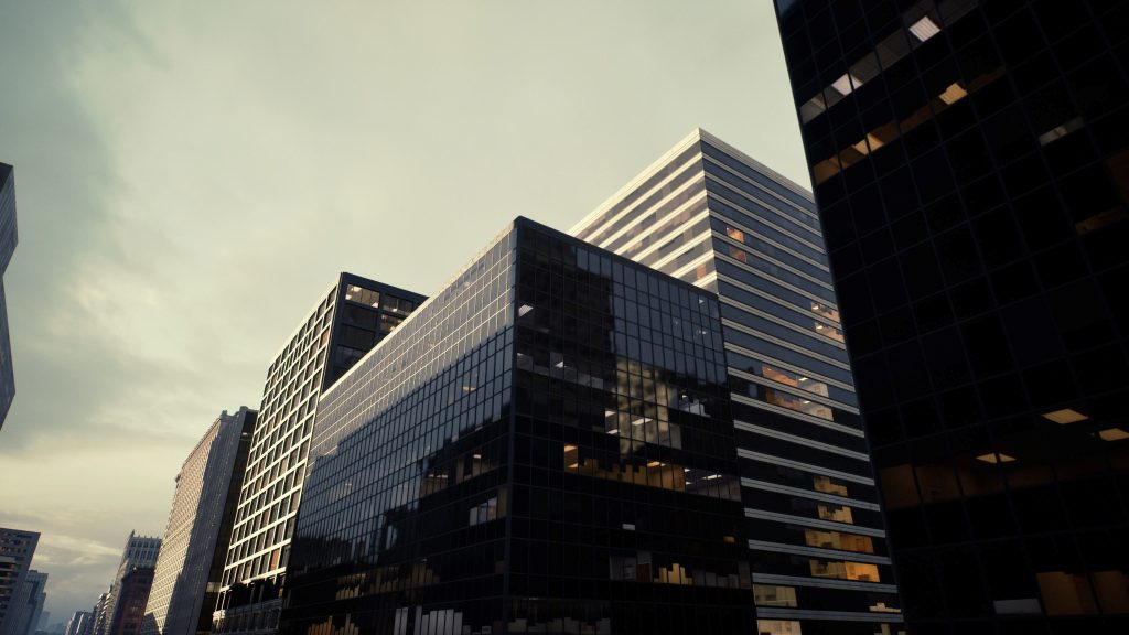 Modern skyscrapers with dark glass and light facades rise against a cloudy sky.