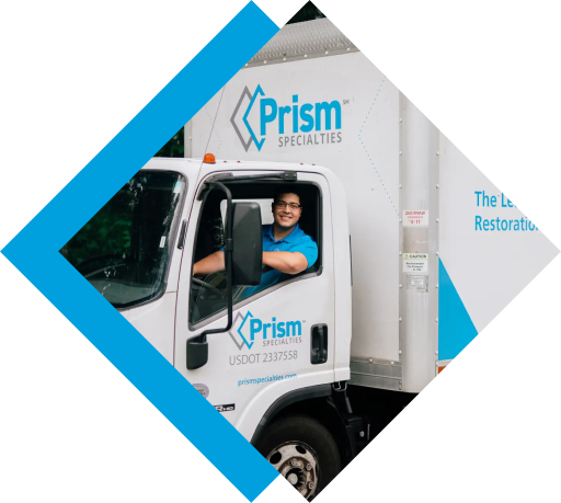 An employee smiles from the driver's seat of a Prism Specialties service truck.
