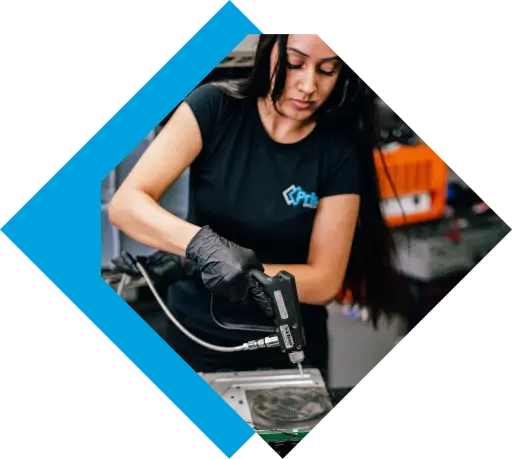 A female technician in black gloves carefully uses a dispensing tool on a metal component. TITLE: