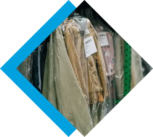 Cleaned garments individually wrapped in plastic bags hang on a rack, ready for customer pickup.