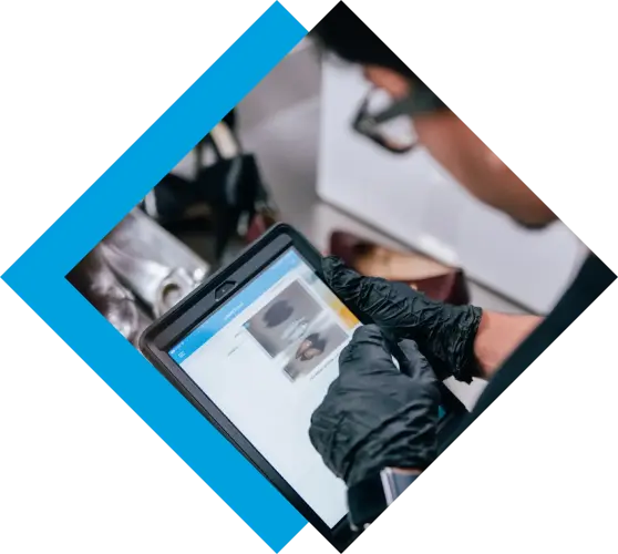 Gloved hands operate a tablet displaying an application with images in a professional setting. TITLE