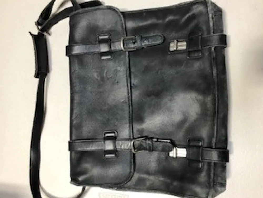 A distressed dark leather messenger bag features a flap closure with two buckled straps and a shoulder strap.